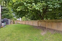 Expansive green lawn framed by a substantial wood privacy fence, featuring a decorative lattice top - 