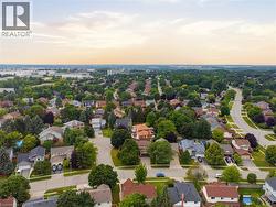 Expansive aerial showcasing a residential area with varied architectural styles, mature tree canopy, and established roadways - 