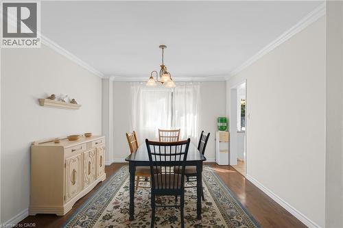 Dining area with dark wood-finish flooring, white crown molding, and a traditional chandelier - 123 Benn Drive, Cambridge, ON - Indoor Photo Showing Dining Room