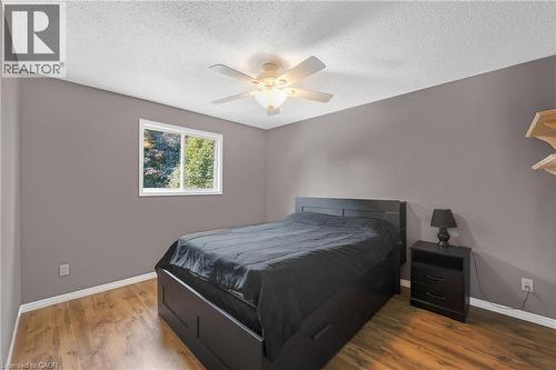 Bedroom featuring wood-finish flooring, a window with exterior tree scenery, a ceiling fan with integrated lighting, and neutral-toned walls - 123 Benn Drive, Cambridge, ON - Indoor Photo Showing Bedroom