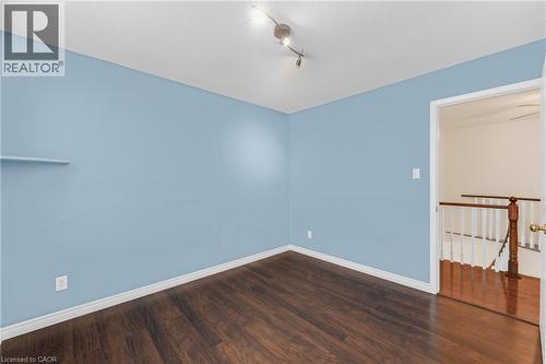 Spacious room featuring a built-in wall shelf, dark wood-finish flooring, and crisp white baseboards - 123 Benn Drive, Cambridge, ON - Indoor Photo Showing Other Room