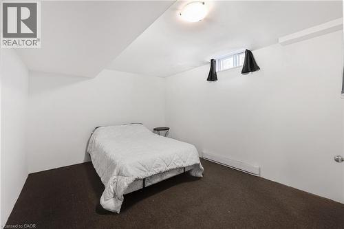 Carpeted room featuring a white ceiling and walls with a small window, built-in baseboard heating, and a flush-mount ceiling light fixture - 123 Benn Drive, Cambridge, ON - Indoor Photo Showing Bedroom