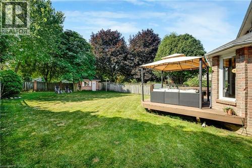 Expansive backyard featuring a large green lawn, mature trees, a wooden deck, and a detached storage shed - 123 Benn Drive, Cambridge, ON - Outdoor With Backyard