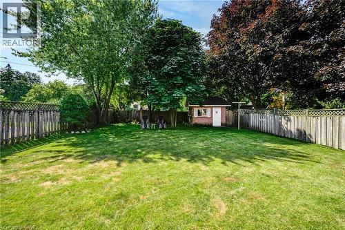 Expansive backyard featuring a manicured lawn, mature trees, and a wooden privacy fence - 123 Benn Drive, Cambridge, ON - Outdoor With Backyard