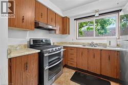 Kitchen featuring wood-finish cabinetry, stainless steel double oven range, dual basin sink, and ample countertop space - 