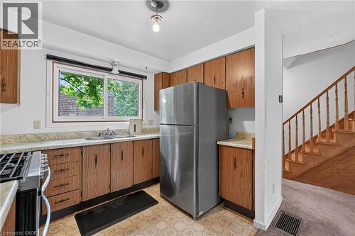Kitchen featuring wood-finish cabinetry, stainless steel refrigerator, and a gas range - 125 Bonaventure Drive Unit# 50, Hamilton, ON - Indoor Photo Showing Kitchen With Double Sink