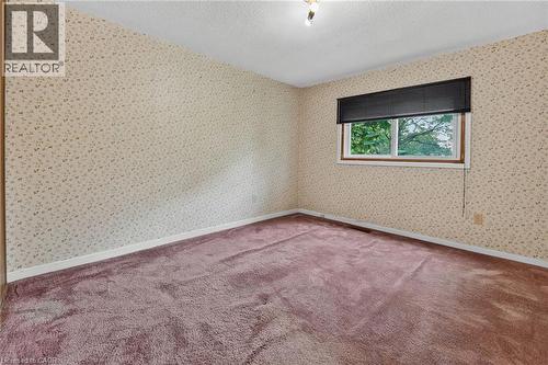 Room featuring patterned wallpaper, textured ceiling, a single window with black blinds, and purple carpeting - 125 Bonaventure Drive Unit# 50, Hamilton, ON - Indoor Photo Showing Other Room