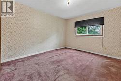 Room featuring patterned wallpaper, textured ceiling, a single window with black blinds, and purple carpeting - 