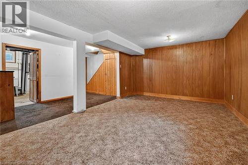 Spacious room featuring wood paneling, white painted walls, and textured carpeting - 125 Bonaventure Drive Unit# 50, Hamilton, ON - Indoor
