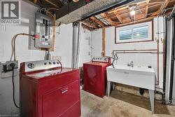 Dedicated laundry area featuring a utility sink, exposed ceiling joists, and a window - 