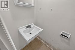 Wall-mounted sink with chrome faucet, framed mirror, and tile flooring - 