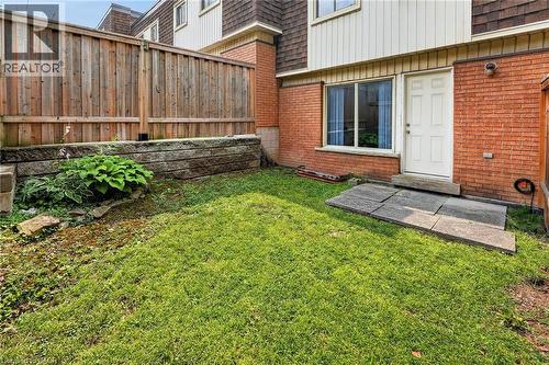 Private backyard space featuring a wood fence, a retaining wall with integrated plantings, and a grass lawn - 125 Bonaventure Drive Unit# 50, Hamilton, ON - Outdoor With Exterior