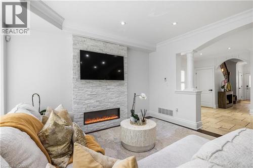Living space featuring a stone-clad fireplace surround with a linear electric fireplace, recessed lighting, crown molding, and an arched entry - 199 Hunter Street W, Hamilton, ON - Indoor Photo Showing Living Room With Fireplace