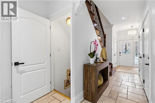 Inviting entryway featuring natural stone tile flooring, a wood-finish staircase with dark banister, recessed lighting, and a front door with decorative glass inserts - 199 Hunter Street W, Hamilton, ON - Indoor Photo Showing Other Room