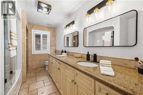 Double vanity featuring stone countertops and two rectangular mirrors with black frames - 199 Hunter Street W, Hamilton, ON - Indoor Photo Showing Bathroom
