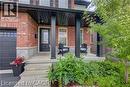 Brick exterior featuring a covered porch, dark entry door with glass insert, black garage door, and established landscaping - 290 William Street, Elmira, ON  - Outdoor 