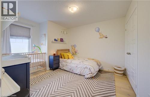 Bedroom featuring light wood-finish flooring, a white paneled door, and a single window with a gray Roman shade - 290 William Street, Elmira, ON - Indoor Photo Showing Bedroom