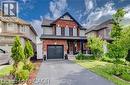 Two-story home featuring a brick and siding exterior, an attached garage, a covered front porch with dark pillars, a paved driveway, and a front lawn with mature greenery - 290 William Street, Elmira, ON  - Outdoor With Facade 