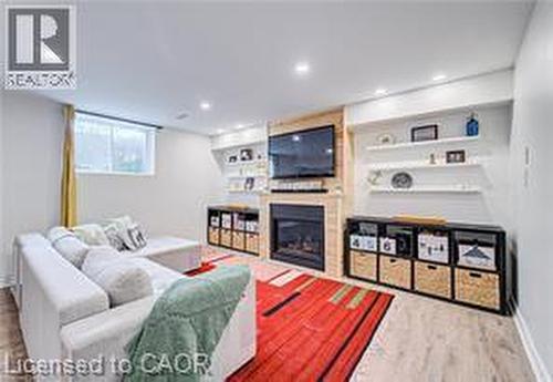 Living area featuring a fireplace, wood-finish flooring, recessed lighting, and wall-mounted shelving - 290 William Street, Elmira, ON - Indoor With Fireplace