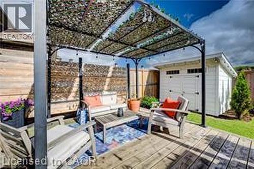Expansive backyard deck featuring a dark metal pergola with a patterned shade cover and string lighting - 290 William Street, Elmira, ON - Outdoor