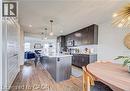 Open-concept kitchen featuring wood-finish flooring, dark wood cabinetry, stainless steel appliances, a center island with seating, and pendant lighting - 290 William Street, Elmira, ON  - Indoor Photo Showing Kitchen 