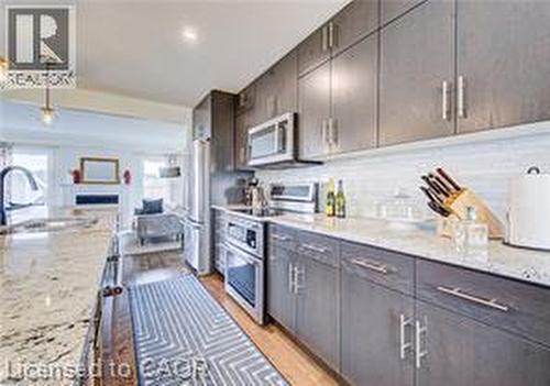 Kitchen featuring wood-finish cabinetry with stainless steel hardware, a light-toned countertop, and stainless steel appliances including a refrigerator and double oven - 290 William Street, Elmira, ON - Indoor Photo Showing Kitchen With Upgraded Kitchen