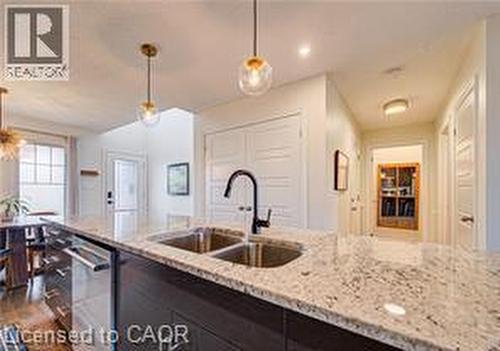 Kitchen island featuring a dual-basin stainless steel sink with a matte black faucet, light-toned stone countertop, and dark wood-finish cabinetry - 290 William Street, Elmira, ON - Indoor Photo Showing Kitchen With Double Sink With Upgraded Kitchen