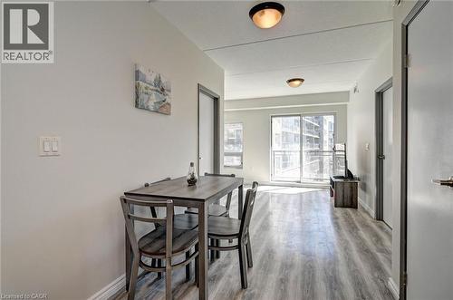 Spacious interior featuring wood-finish flooring, light grey walls, ceiling-mounted flush lighting, and a sliding glass door leading to a balcony - 275 Larch Street Unit# F209, Waterloo, ON - Indoor Photo Showing Dining Room