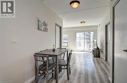 Spacious interior featuring wood-finish flooring, light grey walls, ceiling-mounted flush lighting, and a sliding glass door leading to a balcony - 