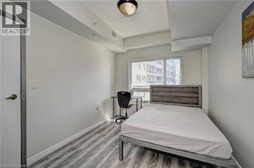 Bright room with a large window, light wood-finish flooring, and a white interior door - 275 Larch Street Unit# F209, Waterloo, ON - Indoor Photo Showing Bedroom