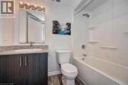 Bathroom featuring a dark wood-finish vanity with a granite-style countertop and an undermount sink - 