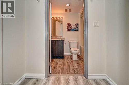 Bathroom featuring a dark wood-finish vanity with a stone-finish countertop, a wall-mounted mirror, and a modern light fixture - 275 Larch Street Unit# F209, Waterloo, ON - Indoor Photo Showing Bathroom