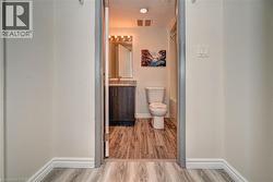 Bathroom featuring a dark wood-finish vanity with a stone-finish countertop, a wall-mounted mirror, and a modern light fixture - 