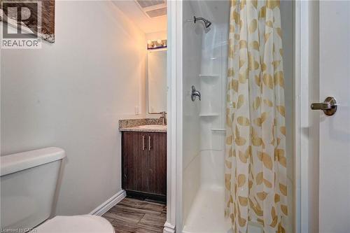 Bathroom featuring a stand-up shower with a showerhead and built-in shelving, a toilet, and a vanity with a surface-mount sink - 275 Larch Street Unit# F209, Waterloo, ON - Indoor Photo Showing Bathroom