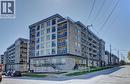 Contemporary multi-story building featuring stone and paneling facade, multiple balconies with glass railings, and a ground-floor retail space with large windows - 275 Larch Street Unit# F209, Waterloo, ON  - Outdoor With Balcony With Facade 