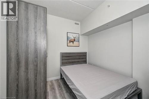 Spacious room with wood-finish flooring, a built-in wardrobe with gray wood-look doors, and a matching headboard - 275 Larch Street Unit# F209, Waterloo, ON - Indoor Photo Showing Bedroom