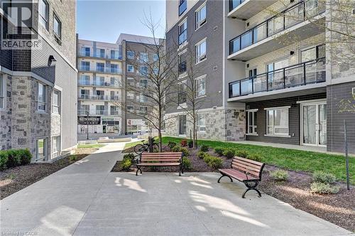 Outdoor common area featuring concrete pathways, manicured lawn, and planted garden beds - 275 Larch Street Unit# F209, Waterloo, ON - Outdoor With Balcony