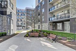 Outdoor common area featuring concrete pathways, manicured lawn, and planted garden beds - 