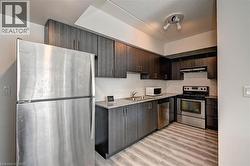 Contemporary kitchen featuring dark wood-finish cabinetry, speckled countertops, and a white subway tile backsplash - 