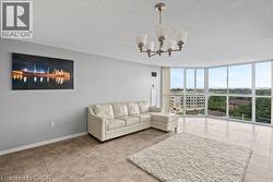 Spacious living area featuring floor-to-ceiling windows, a chandelier with frosted glass shades, and light-toned tile flooring - 