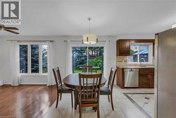 Open-concept dining area with wood-finish flooring, a contemporary ceiling light fixture, and large windows - 
