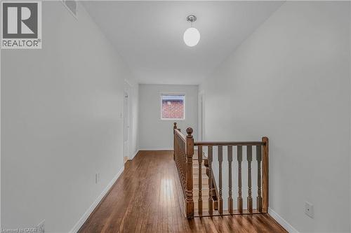 Upper landing featuring wood-finish flooring, a wood banister, a single light fixture, and a window providing natural illumination - 888 Paisley Road, Guelph, ON - Indoor Photo Showing Other Room