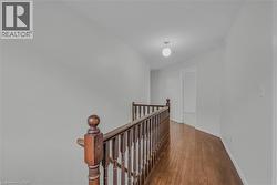 Upper-level hallway with wood-finish flooring, a traditional wood-spindle banister, and recessed lighting - 