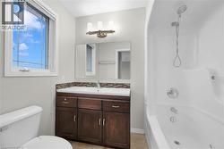 Bathroom featuring a window with privacy blinds, dark wood-finish vanity with ample storage, integrated white sink, mosaic tile backsplash, and a combination shower/tub with a handheld showerhead - 