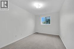 Spacious room with light gray carpeting, a bright window, white baseboards, and a flush mount ceiling light - 