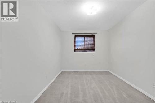 Room featuring light gray carpet flooring, neutral painted walls, and a window with dark wood-toned blinds - 888 Paisley Road, Guelph, ON - Indoor Photo Showing Other Room