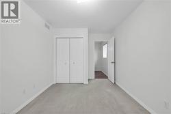 Carpeted room with light gray walls, featuring a bi-fold closet with white panels and gold-toned knobs - 