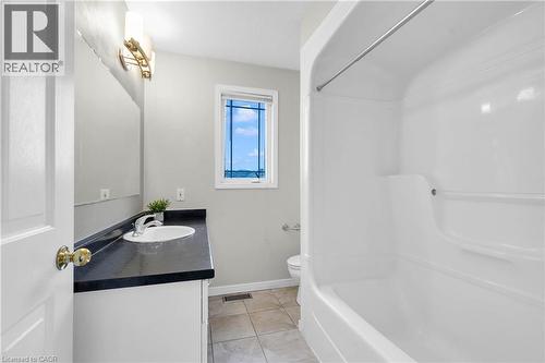 Full bathroom featuring a white vanity with dark countertop, an integrated sink, and an overhead light fixture - 888 Paisley Road, Guelph, ON - Indoor Photo Showing Bathroom