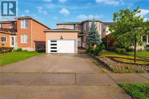 Brick exterior with a modern white garage door featuring horizontal window panels - 888 Paisley Road, Guelph, ON - Outdoor