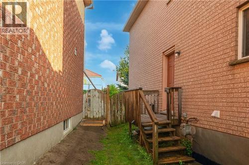 Exterior brick siding with a wooden deck and staircase - 888 Paisley Road, Guelph, ON - Outdoor With Exterior